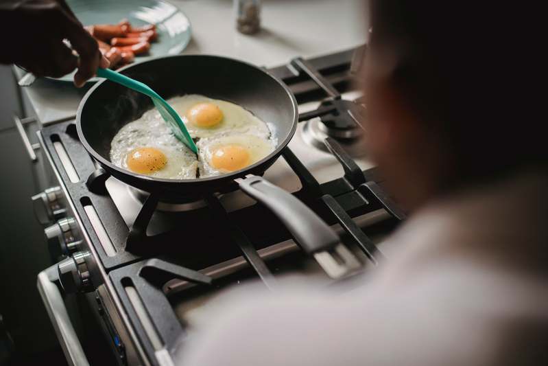 Close-up of hands using an egg poacher over a simmering pot